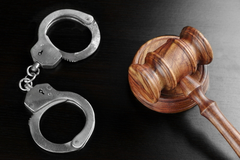 Handcuffs and a gavel on a lawyer's desk.