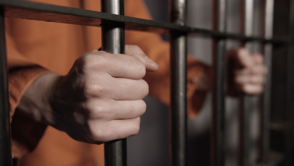Man showing hands behind bars.