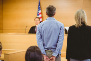 Man on handcuffs standing in front of the judge.