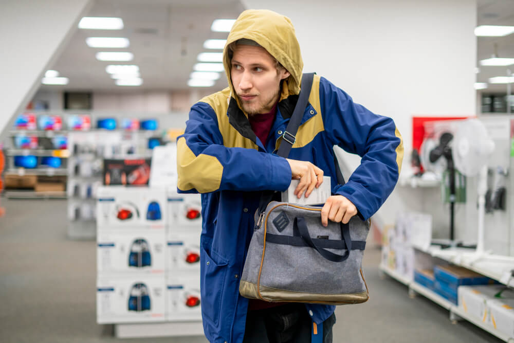 Shoplifter in the electronic store supermarket stealing new gadget.