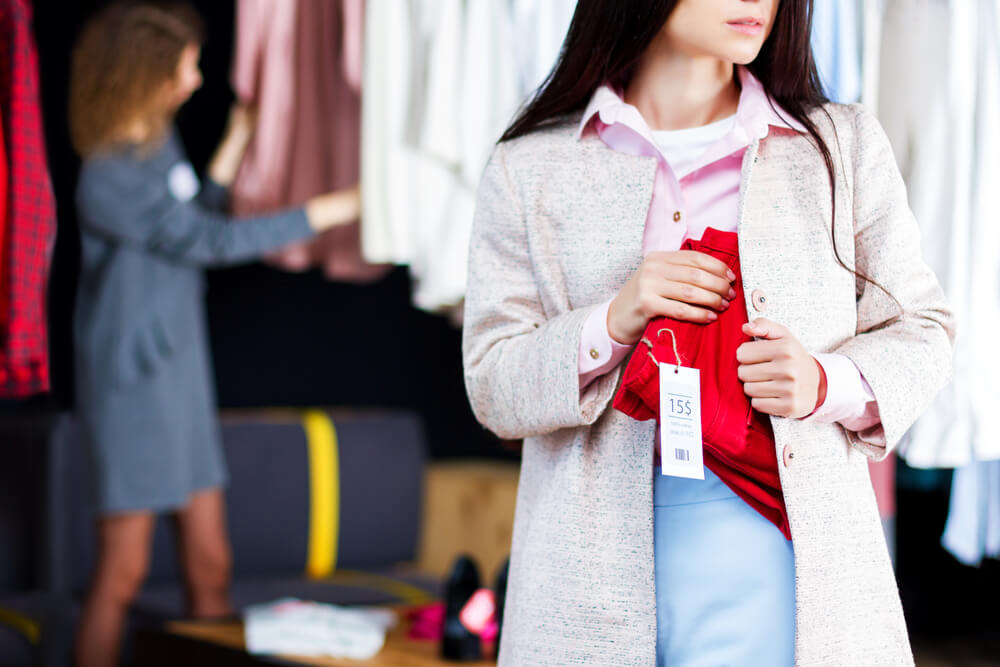 Woman shoplifting red pants at macys.