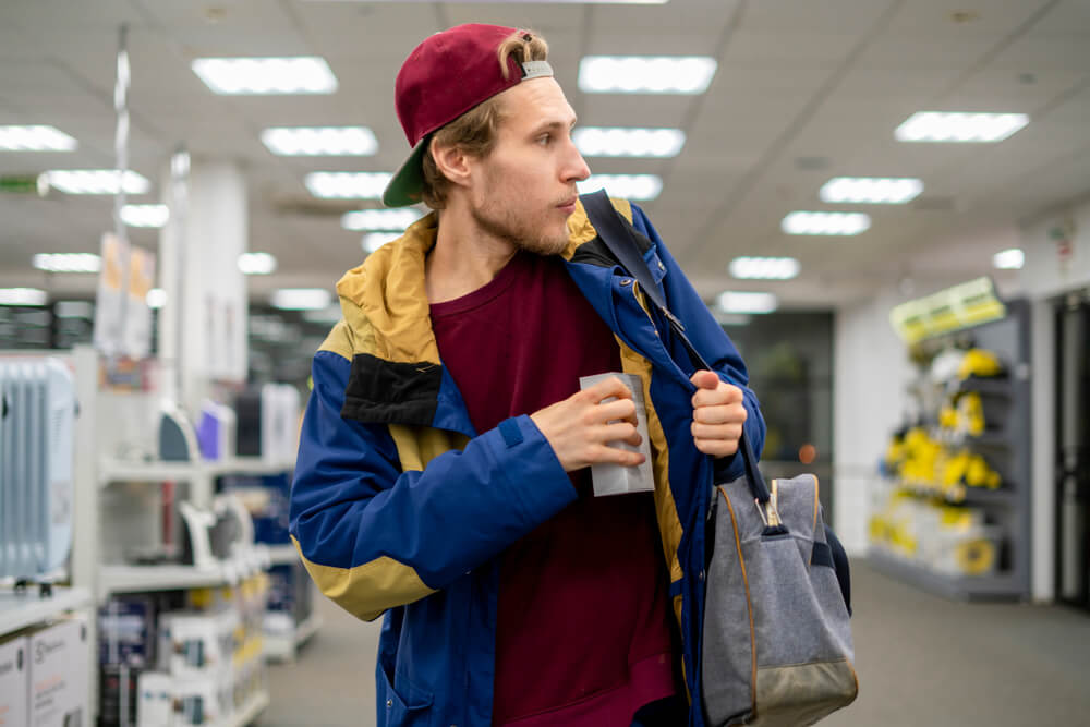 Shoplifter in the electronic store supermarket stealing new gadget.