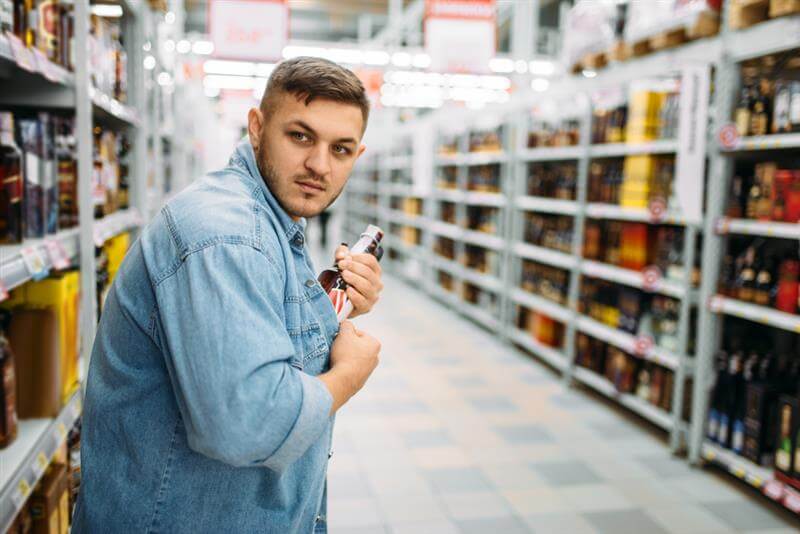 Man shoplifting expensive wine in the grocery