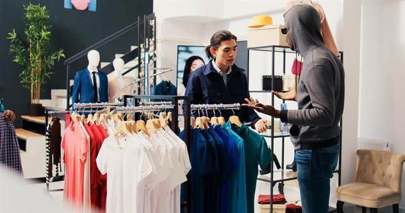Man with a hoodie shoplifting garments.