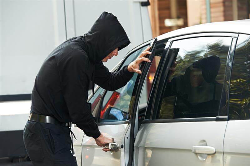 Thief stealing automobile car at daylight street in city.