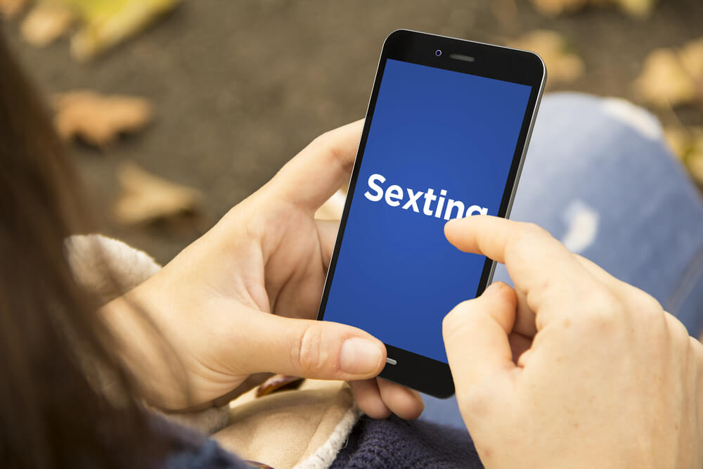 A girl using a digital generated phone with sexting on the screen.